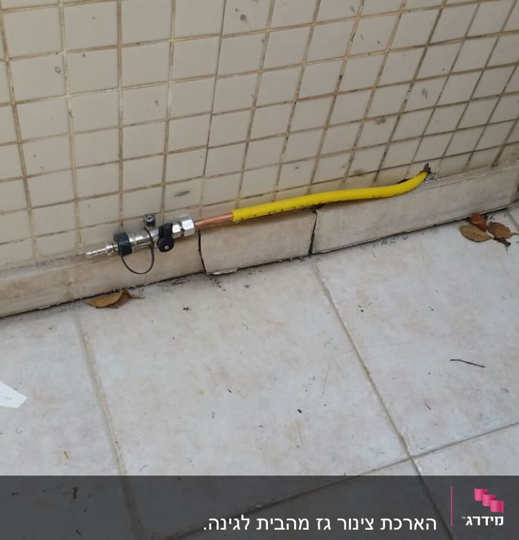 צינור גז צהוב מחובר לשסתום על קיר אריחים